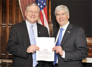 Michigan Gov. Rick Snyder (left) and state Sen. Rick Jones with a copy of the state’s new law banning ergonomics regulation. 