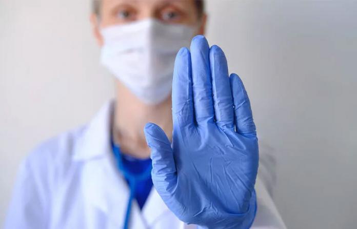 Health care worker with latex glove to say stop