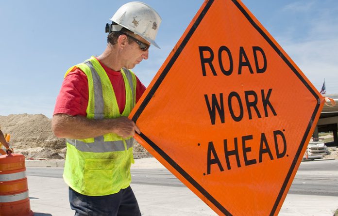 Road Work Ahead sign and construction worker