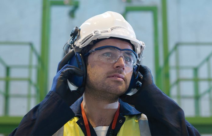 Industrial worker putting on earmuff hearing protection