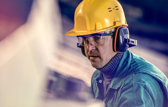 Older worker wearing hard hat and hearing protection