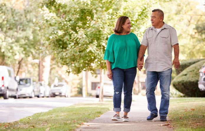 Older Latino couple walking in suburbs