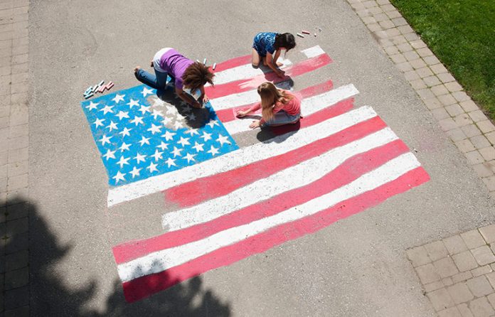 Girls drawing American flag on driveway with chalk