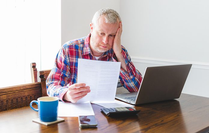 Man paying bills in kitchen stressed